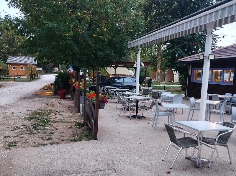 La terrasse du restaurant au bord de l'allée du camping de l'Arquebuse