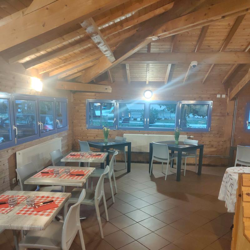 La salle du restaurant sous la charpente en bois, avec ses tables dressées