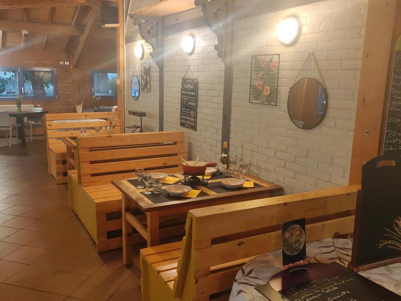 La salle du Bord de Saône : banquettes en bois, mur de briques claires et table dressée pour la fondue